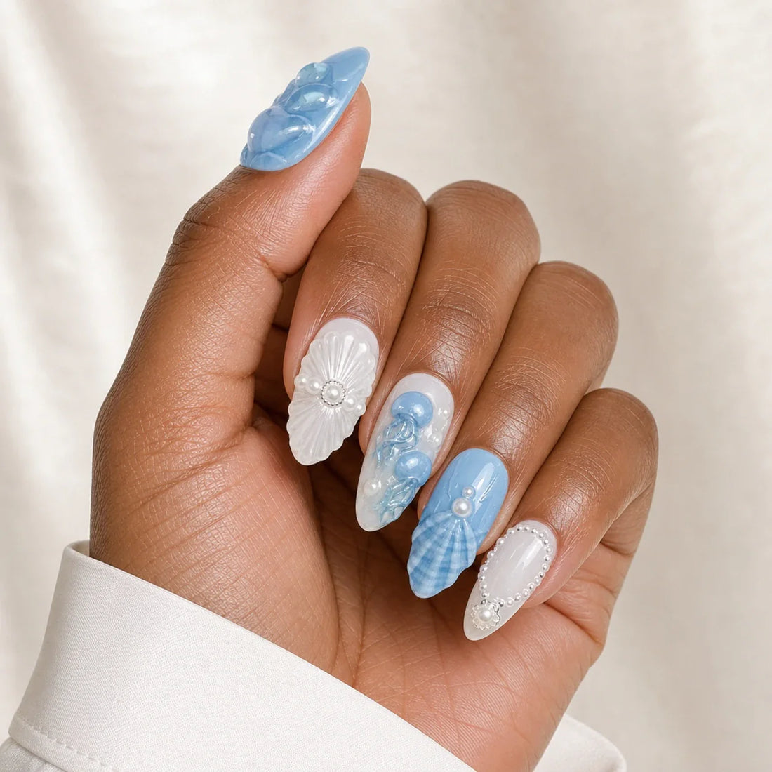 Tidal Cameo ocean press-on manicure on one medium-brown hand