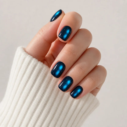 Twin Nebula blue press-on manicure on one curled hand