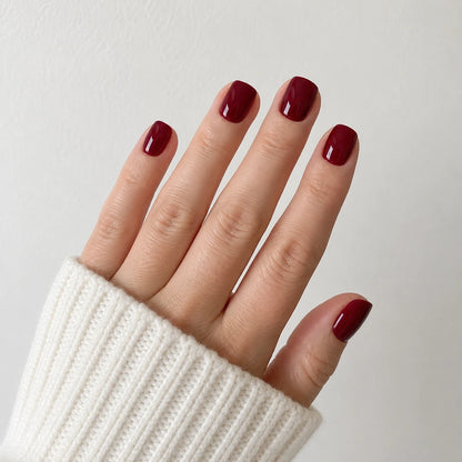 Velvet Merlot glossy wine red short square press-on nails shown on an open hand