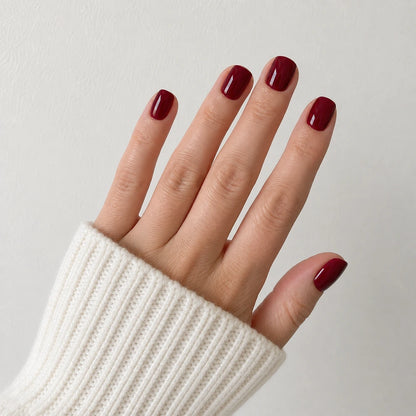Velvet Merlot glossy short square wine red press-on nails shown on a raised open hand