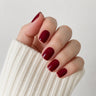 Velvet Merlot short square wine red press-on nails in a close-up curled hand view