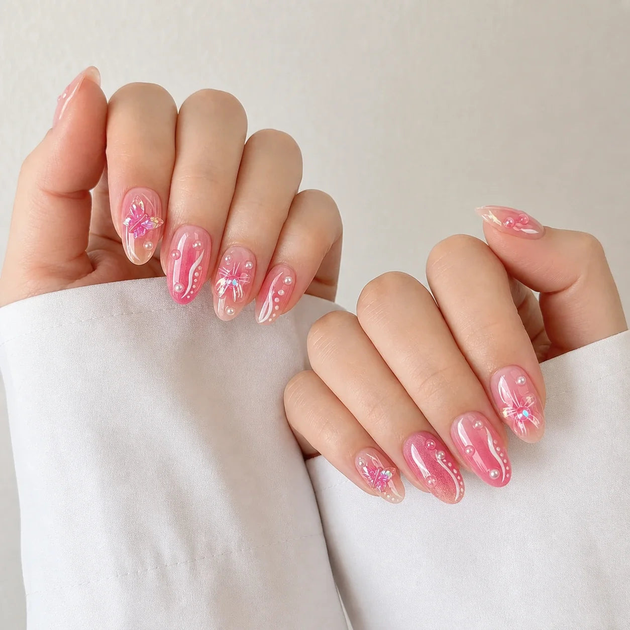 Winglight pink butterfly press-on manicure on two softly curled hands